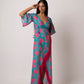 Close-up side angle of model in floral blue and pink wrap dress, highlighting neckline, sleeve, and waist tassels.