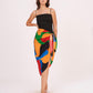 Full-length shot emphasizing the high leg slit and the intricate waist knot. The Sexy Sarong Dress combines a simple black top with a bold, colorful wrap bottom.