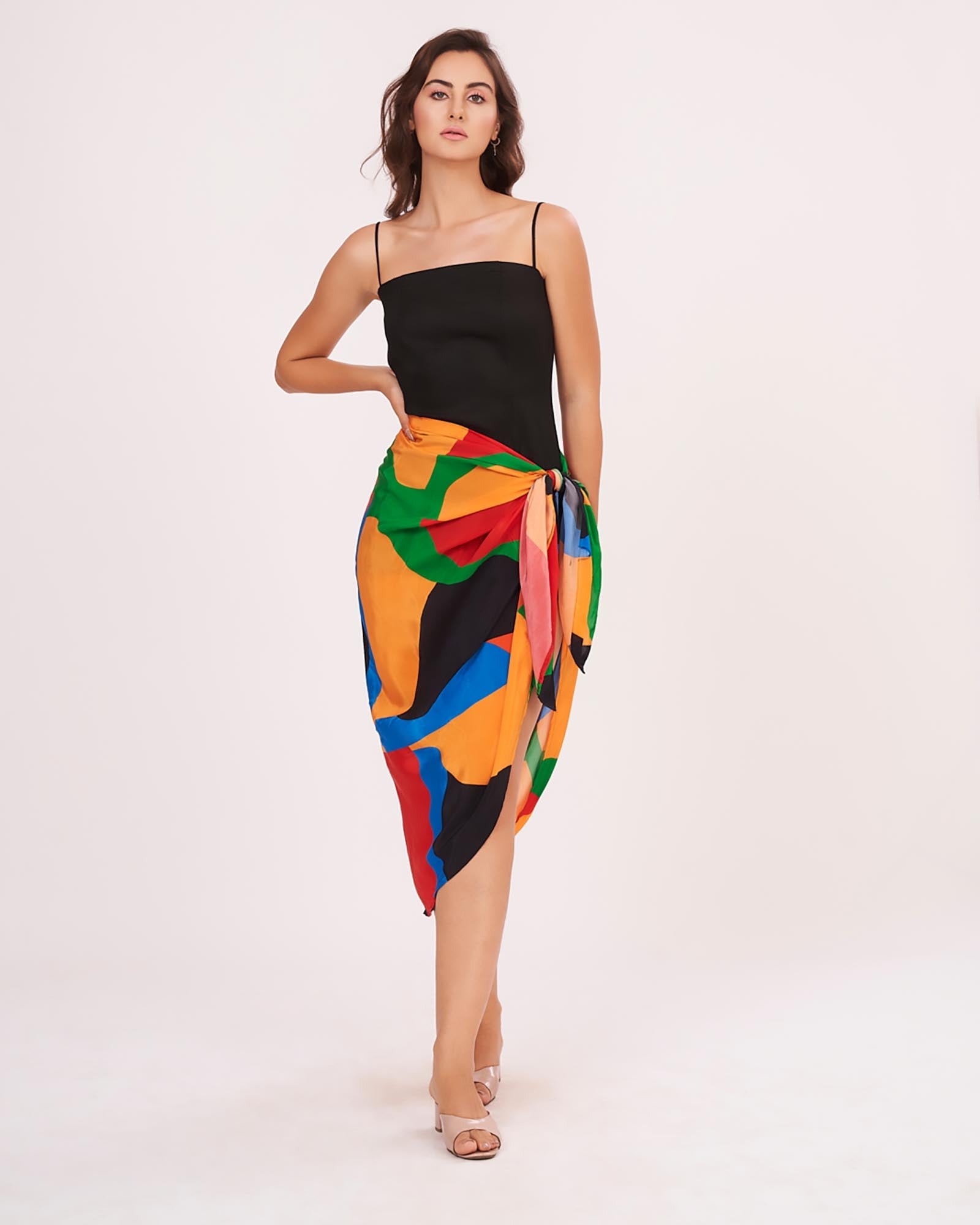 Full-length shot emphasizing the high leg slit and the intricate waist knot. The Sexy Sarong Dress combines a simple black top with a bold, colorful wrap bottom.