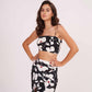 Model poses with hands on waist, showcasing the strap shoulder black floral crop top and matching wrap skirt.
