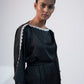 Close-up of black mini kimono dress with boat neck, shell embroidery, and kimono sleeves.
