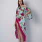 Walking pose of model in asymmetric hem beach dress with playful fringes and bohemian print, hands gently at sides.