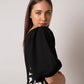 Close side angle of one-shoulder black mini dress highlighting shell-embellished side panel.