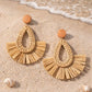 Brown rattan geometric earrings featuring a woven teardrop center and a fanned raffia base.