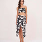 Model posing with hands on side, showing off the bold floral print and ruched details of the black skirt set