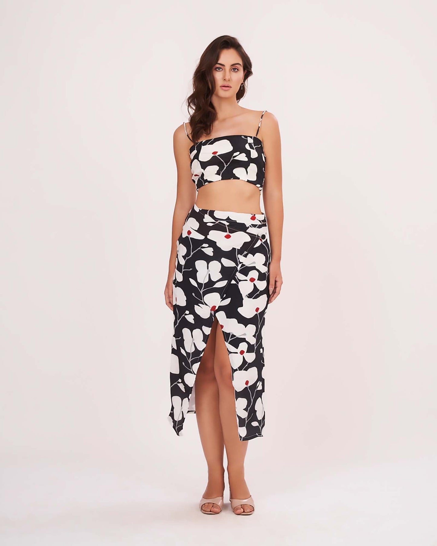 Model posing with hands on side, showing off the bold floral print and ruched details of the black skirt set