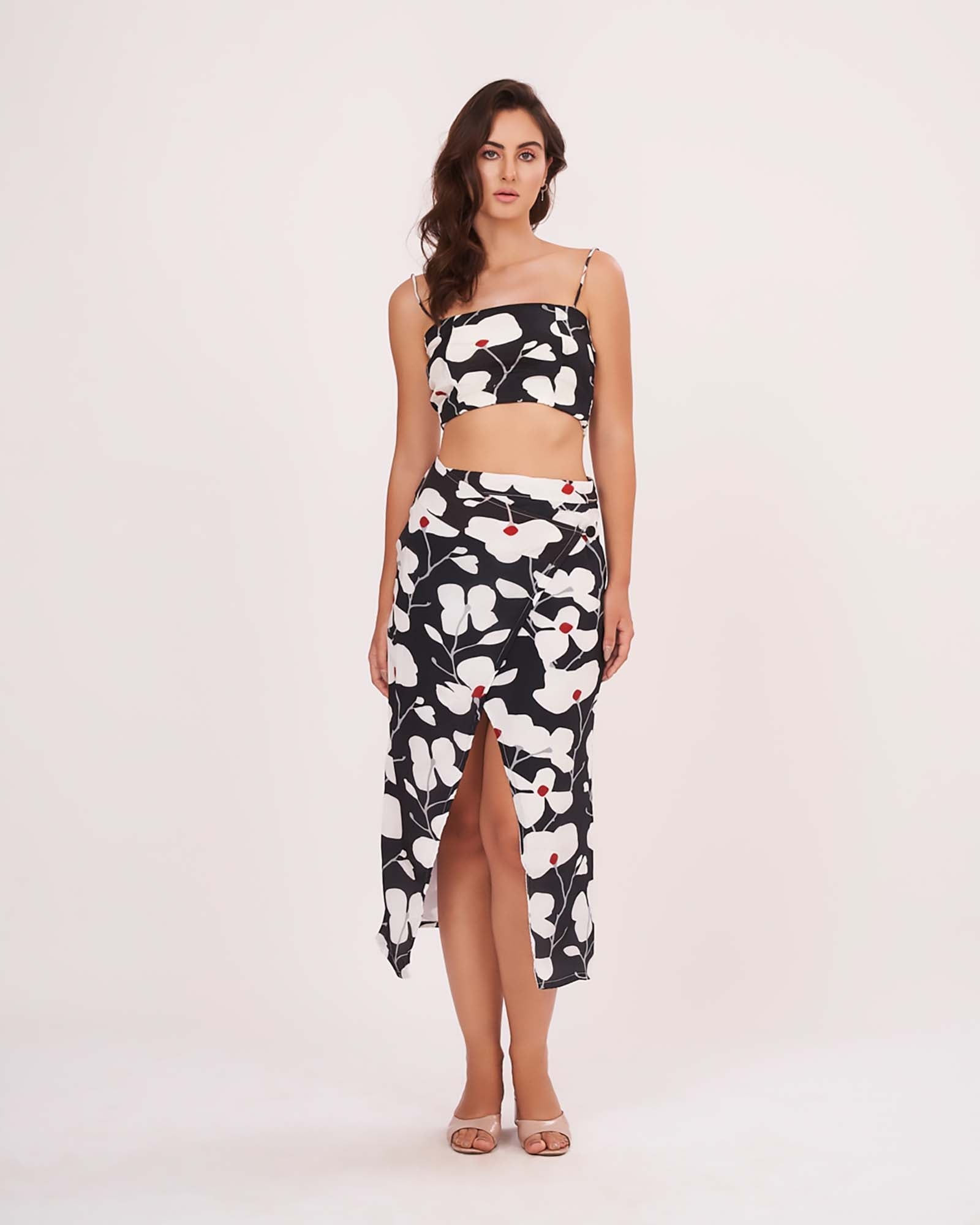 Model posing with hands on side, showing off the bold floral print and ruched details of the black skirt set