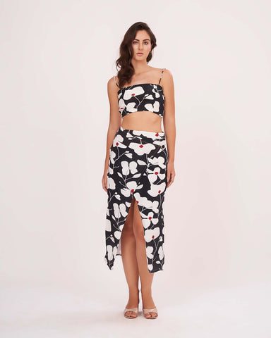 Model posing with hands on side, showing off the bold floral print and ruched details of the black skirt set