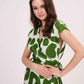 V-neck wrap dress showcasing a bold green abstract print on a crisp white background with a crossover bodice.