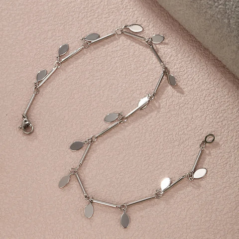 A refined sterling silver anklet featuring a series of polished, flat oval charms that catch the light, perfect for adding a sophisticated sparkle to  a cocktail party.