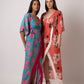 Standing pose of model in blue floral muslin wrap dress with arm at the back, emphasizing structure and relaxed fit