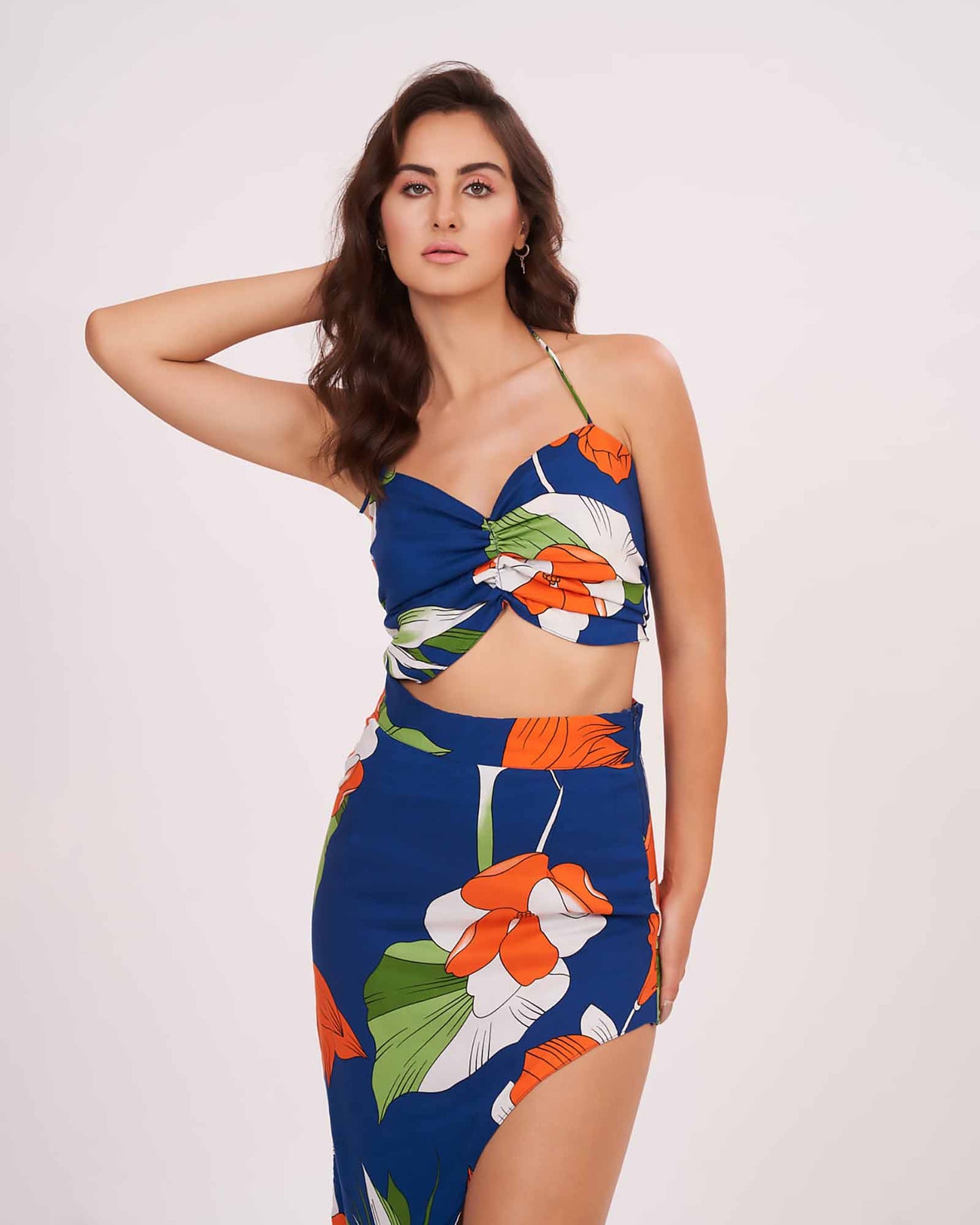 Blue halter-neck crop top featuring a twisted bust detail and vibrant orange and white floral print.
