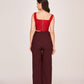 Back view of a red corset top with a back zip closure paired with brown trousers