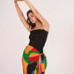 Close-up of the side knot detail that defines the waist and secures the flowy wrap skirt. The Sexy Sarong Dress features a striking mix of primary colors against a black base.