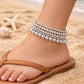 A stylish set of stacked silver-toned seed bead anklets in a mix of metallic and iridescent finishes, perfect for adding a subtle sparkle to your casual weekend outfits or a day at the beach.