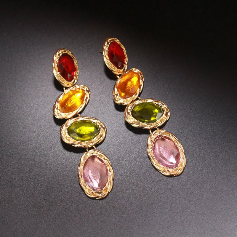 A pair of striking drop earrings featuring a bold color-block design with segments of translucent amber, deep teal, and clear glass, perfect for adding a sophisticated pop of color to a creative office look or an art gallery visit.