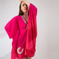 Pink kaftan dress in playful pose with one hand on head and other raised, showcasing flowy fit.