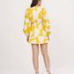 Back view of yellow abstract wrap dress with tie-up detail and full balloon sleeves.