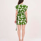 Rear view of a model wearing a short-sleeved mini dress featuring a bold green and white abstract pattern and a side-tie waist.